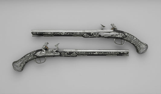 Two ornate flintlock pistols with silver inlay on a plain grey background